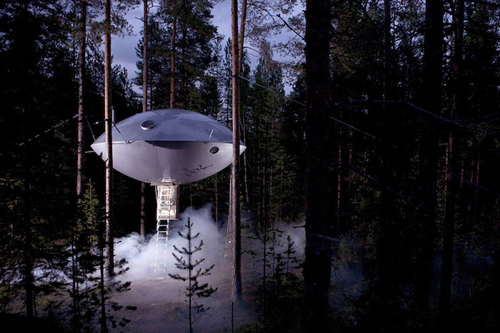 UFO shaped tree house, made from silver metal, suspended over the ground from several trees, and accessible through a ladder, cool tree houses, inside a dark forest 