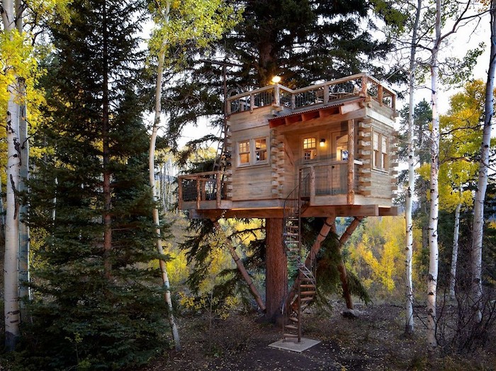 winding staircase leading to a backyard treehouse, built on several large trees, wooden structure with two terraces