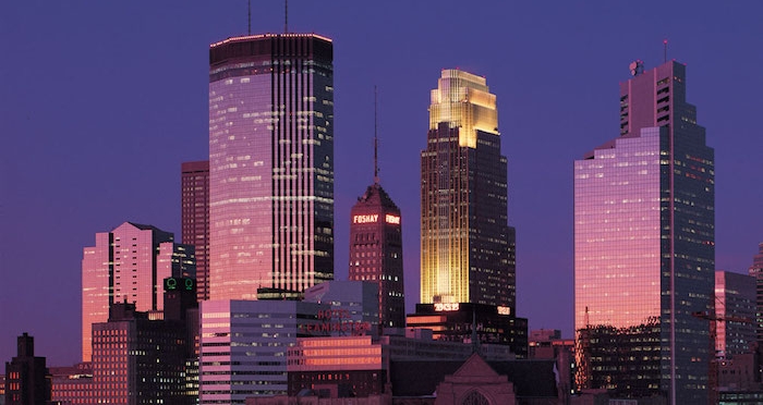 minneapolis at dusk, skyscrapers and other buildings, bathed in pink and purple light, postmodern design, one building lit in yellow