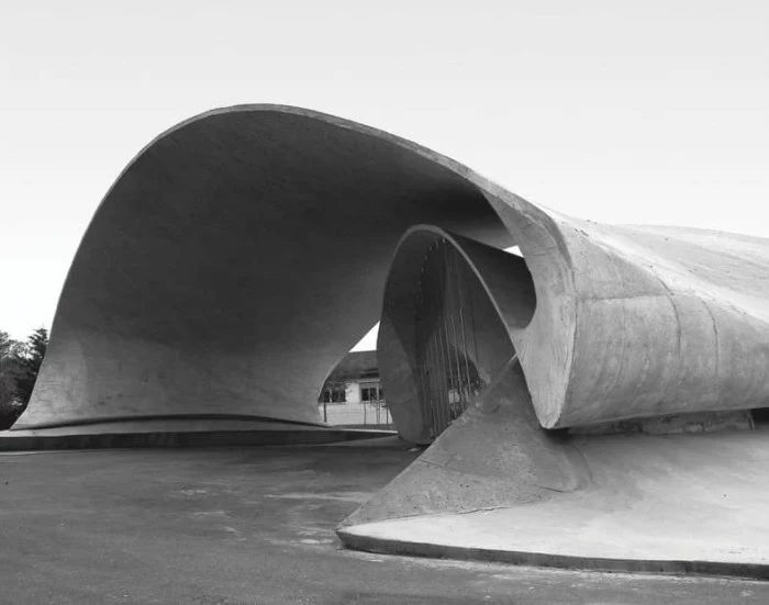 bus stop in spain, made from concrete, with asymmetrical wave-like shapes, seen in a greyscale image