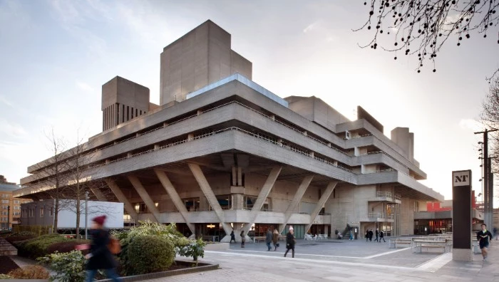 denys lasdun's national theatre, in london england, brutalist art, large multi-storey building, made of grey concrete, and supported by several concrete beams
