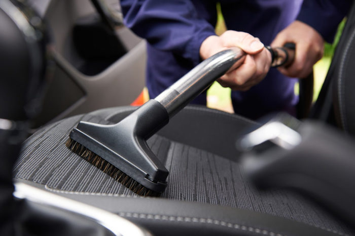 a man is cleaning the seats of a car with black interior