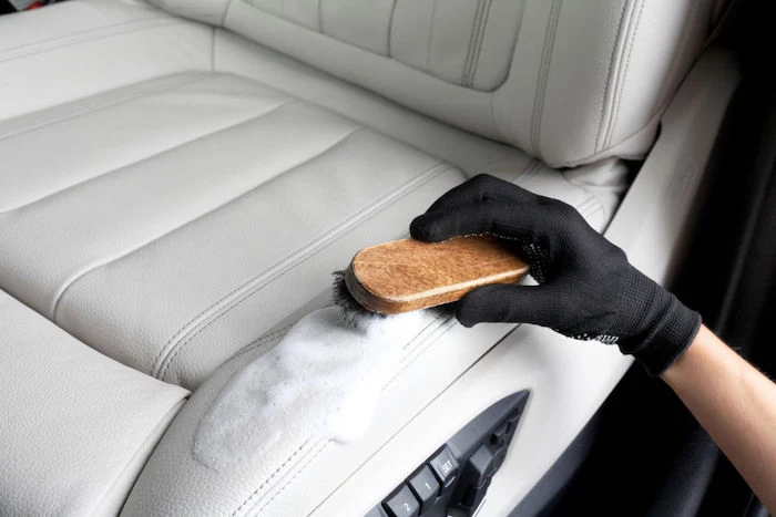 cleaning the leather seats of a vehicle with a special paste and a soft brush