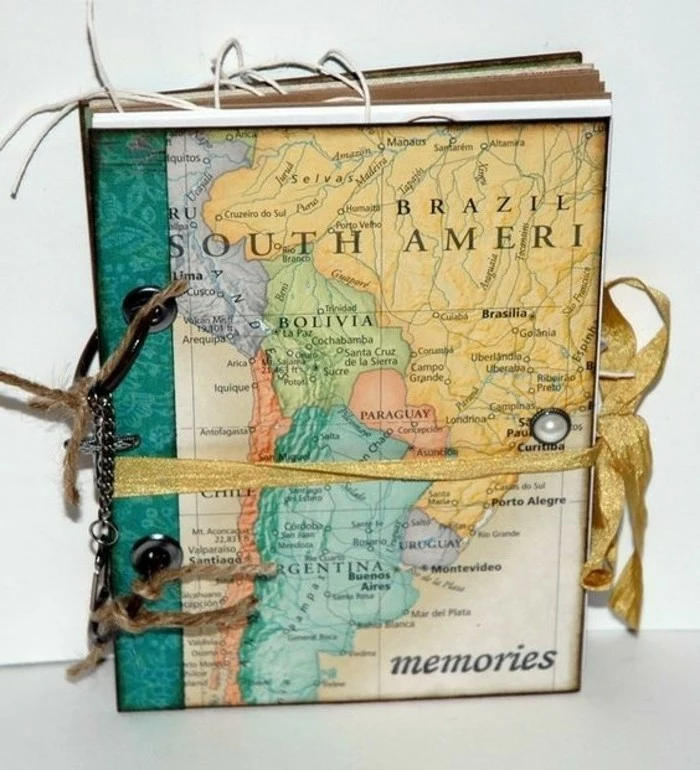 adventure journal, notebook, colorful map stuck on cover, golden ribbon, pearl sicker, rope and chain details, light background 