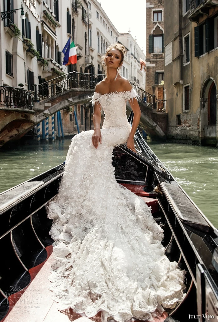vintage wedding dresses, young brunette woman sitting on a gondola, sailing on a canal in venice, wearing long white frilly wedding dress with lace and embroidery