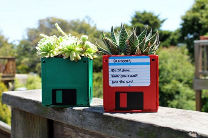 plant pots made to look like floppy disks, placed on a ledge, in green and red, green garden background