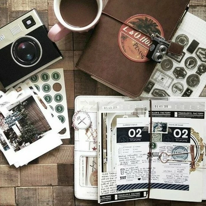 scrapbooking made simple, an old camera, two journals, one brown, closed, tied with string and lock, the other open, cutouts, stamps, stickers, photos