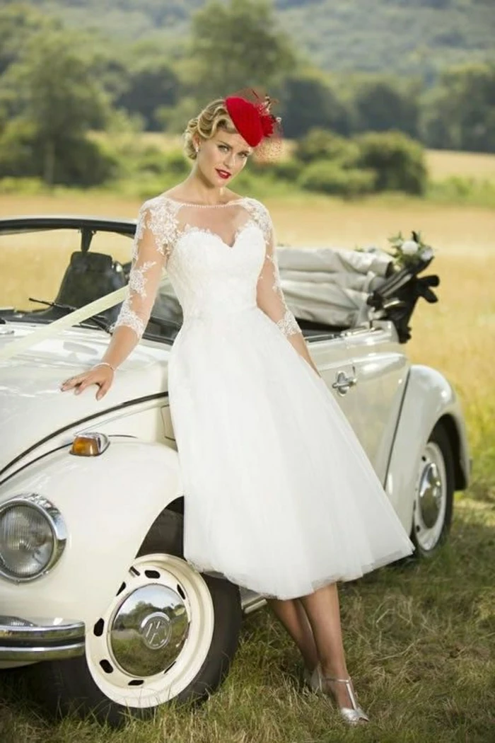 tea length dresses, bride with vintage 1950s dress red cap and silver shoes, leaning on an old white convertible car decorated with white bow, green fields and trees