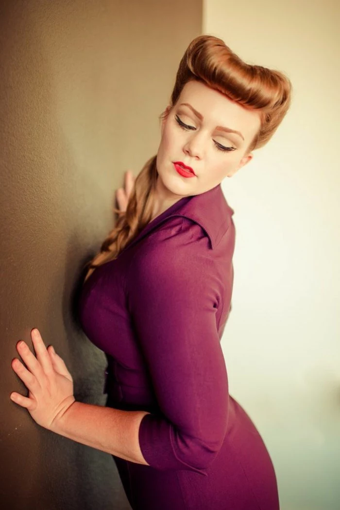 vintage hairstyles, woman with copper ginger hair, ponytail and curled bangs, wearing a purple-maroon dress, leaning on wall with closed eyes