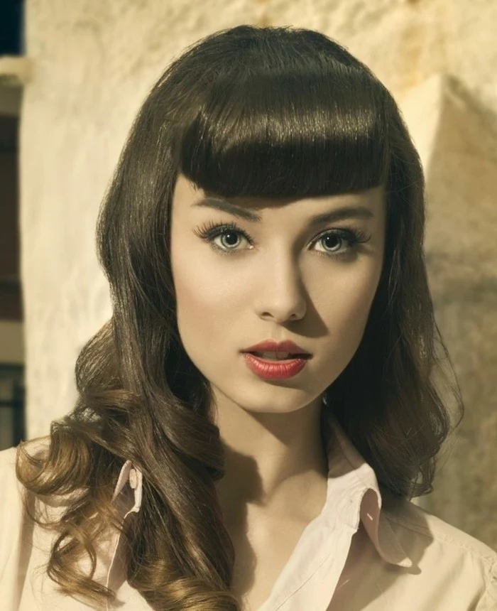 betty bangs, pale woman with heavy make up and dark retro-styled shoulder-length hair, red lipstick fake lashes light shirt