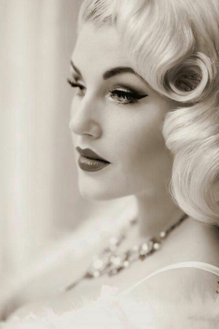 black and white image of a blonde woman, retro curls and heavy make up, eyeliner and lipstick, mascara and fake eyelashes