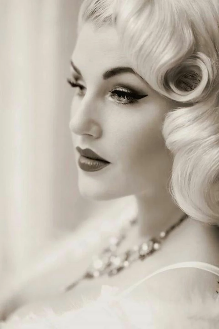 black and white image of a blonde woman, retro curls and heavy make up, eyeliner and lipstick, mascara and fake eyelashes
