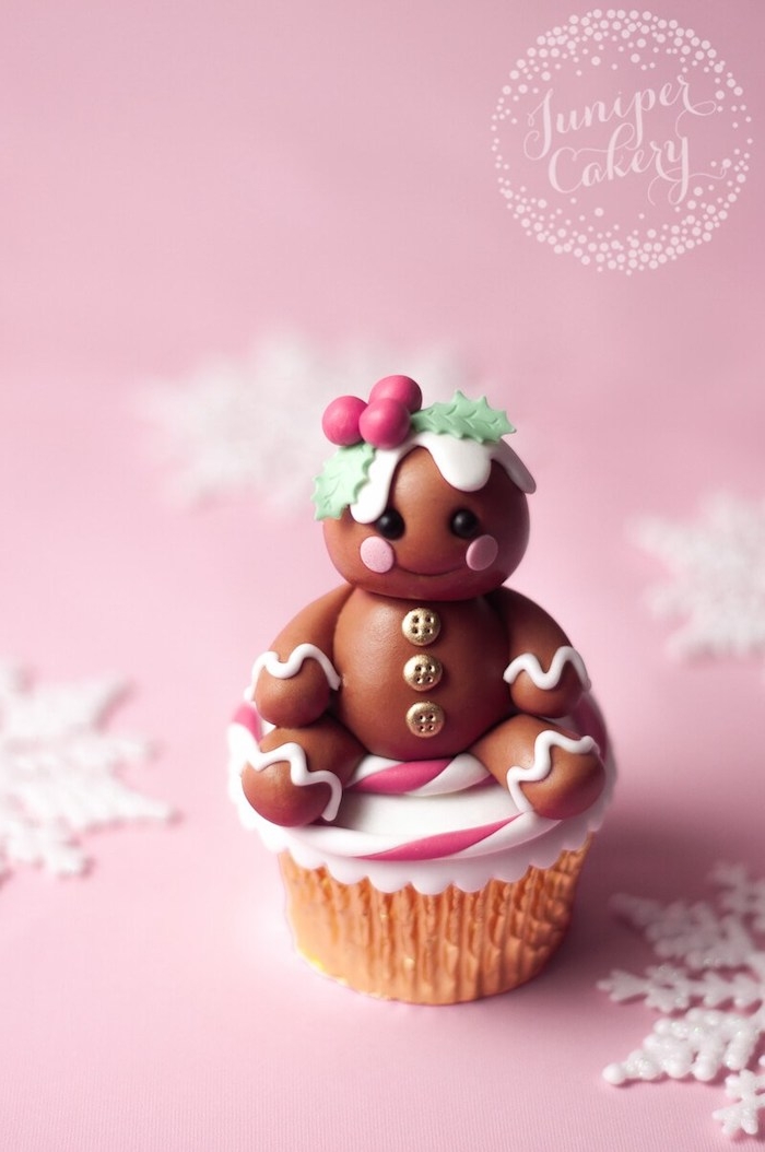 cupcake with golden wrapper, decorated with a little brown fondant doll-like shape, golden buttons and holly in hair