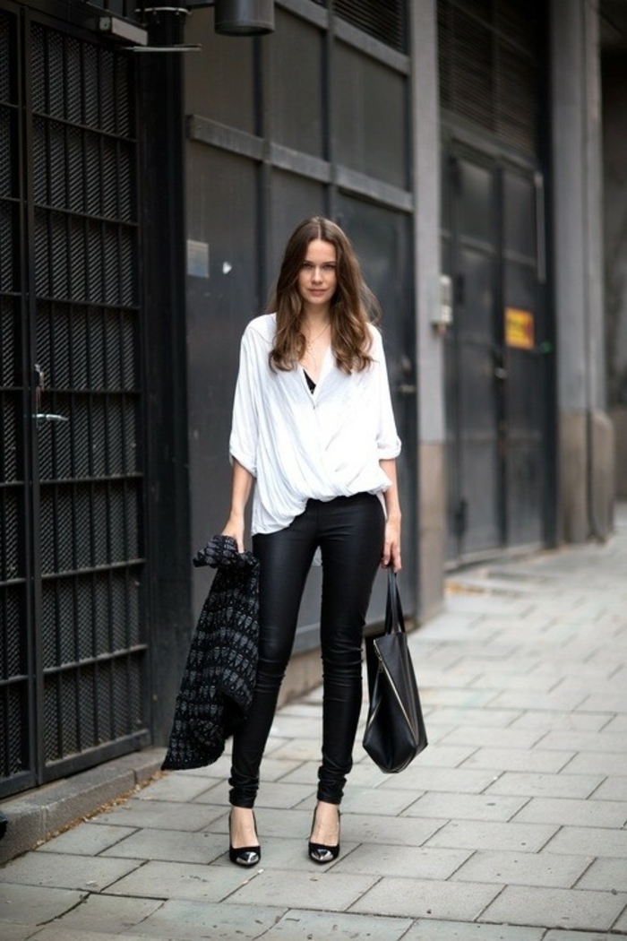 business casual attire for women, brunette woman wearing black skinny trousers, wide-fitting white shirt and black top, holding black and grey cardigan and black leather bag