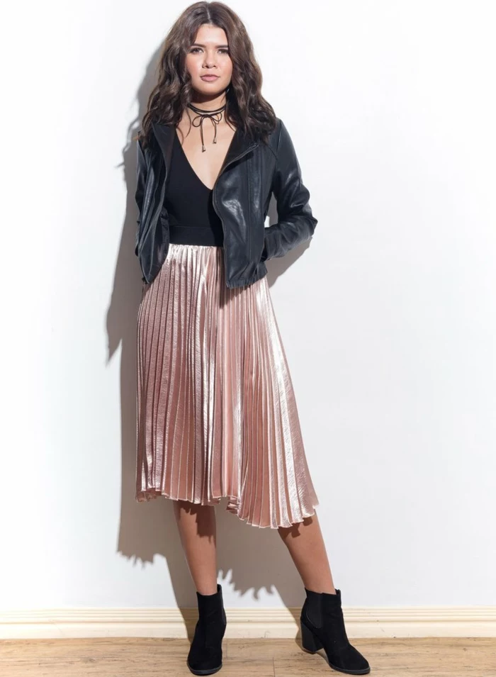 casual business attire, curly-haired brunette with shiny pink pleated ankle-length skirt, black leather biker jacket over black top, chocker and black ankle boots