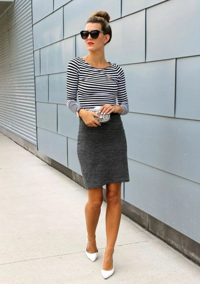 business casual attire for women, dark grey mini skirt, white and black striped top, white high heels and small clutch, worn by woman with sunglasses and hair bun