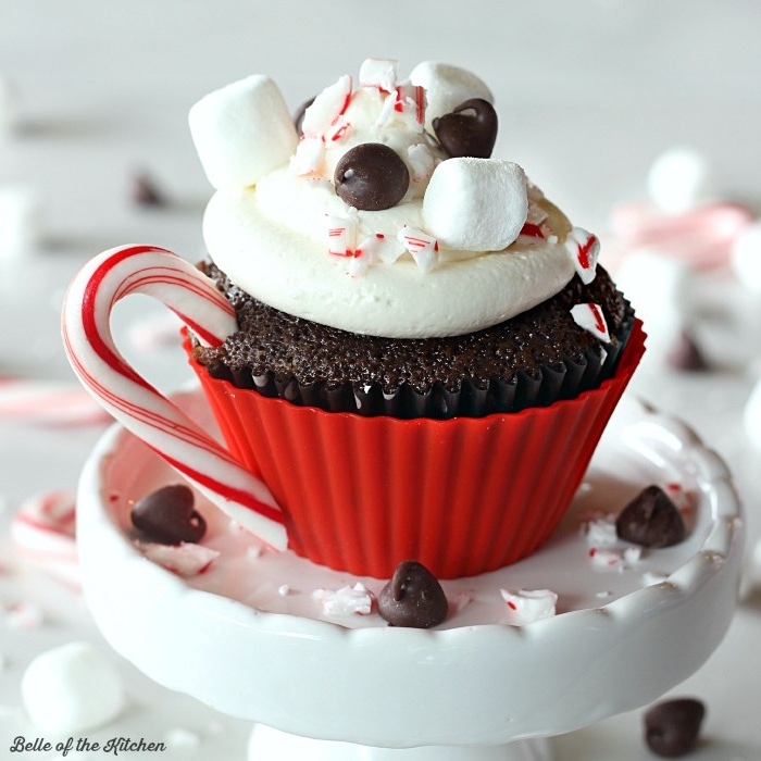 christmas cupcakes, chocolate cupcake in a red cupcake mold, with white frosting marshmallows chocolate chips and peppermint candy cane