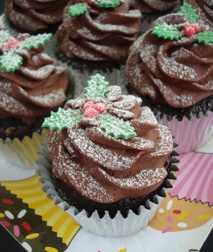 chocolate cupcakes images, several chocolate cupcakes with chocolate frosting, decorated with fondant hollies and dusted with powdered sugar