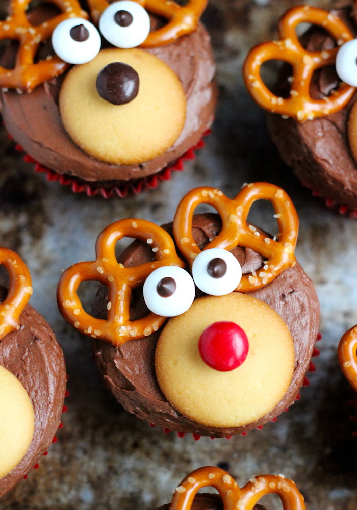 holiday cupcakes, close up of several cupcakes decorated with chocolate icing, yellow cookies candies and pretzels, made to look like reindeer