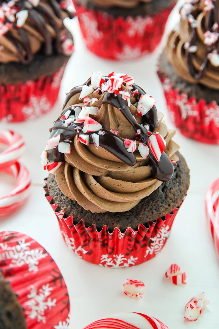 christmas cupcakes, several chocolate cupcakes with creamy chocolate frosting, chocolate syrup drizzle and crushed peppermint candies