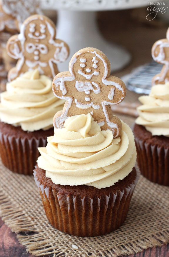 cupcake ideas, several dark cupcakes with light yellow creamy icing, decorated with gingerbread men cookies, on burlap tablecloth wooden table