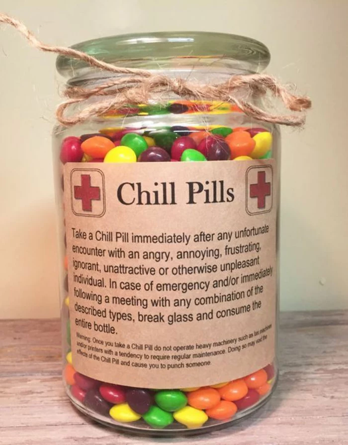 xmas gifts, a clear jar containing many colorful candies, tied with simple string, with a sticker featuring medical crosses and saying chill pills