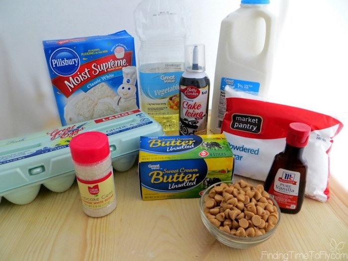 cupcake ideas, pack of eggs near flour and milk and oil, butter next to sugar and chocolate icing, sprinkles and vanilla essence, on a light wooden table