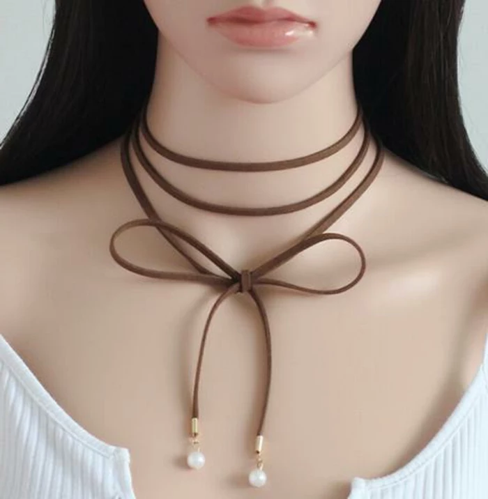 brown leather chocker, wrapped several times around a mannequin's neck and tied in bow, with pearl details