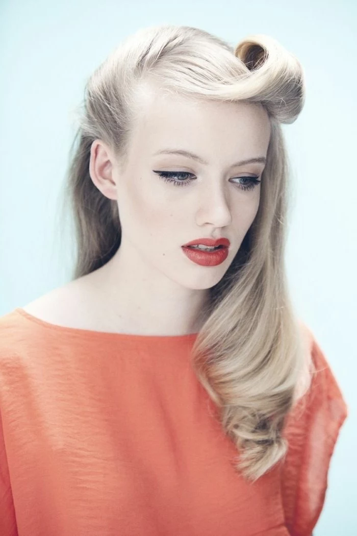 pinup hair, pale woman with light blonde hair, one victory roll and slight curl, red lipstick and eyeliner, wearing pale coral red top