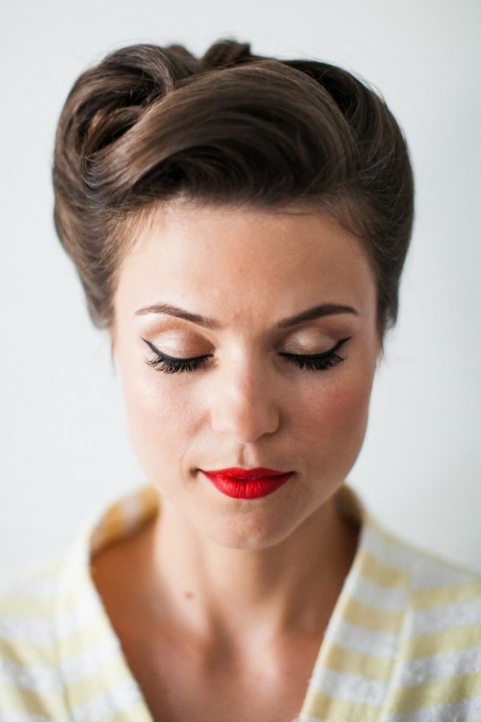 brunette woman with closed eyes, wearing eyeliner and red lipstick, retro updo hairstyle, yellow and white striped top