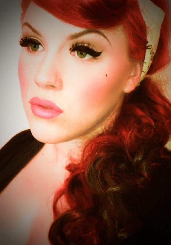 close up of a filtered image of a woman, red hair and bold black eyeliner, pink lipstick beauty spot and blush, black top