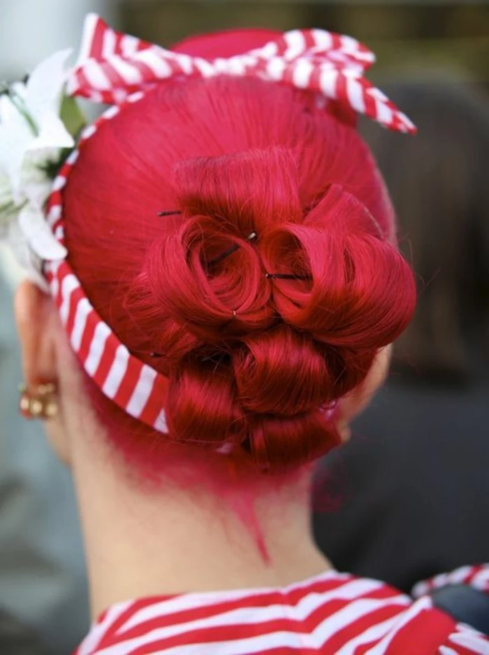 back view of red hair tied up in a hair bun made of curls, striped red and white hair band with bow, big white flower and earrings, striped red and white top