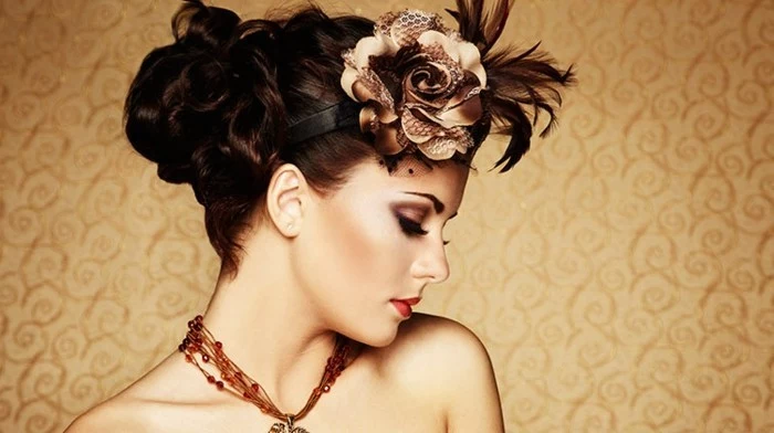 woman with retro updo, brunette hair with brown fake rose ornament and dark feathers, close up in profile, nude shoulders and an amber necklace, heavy eye make up