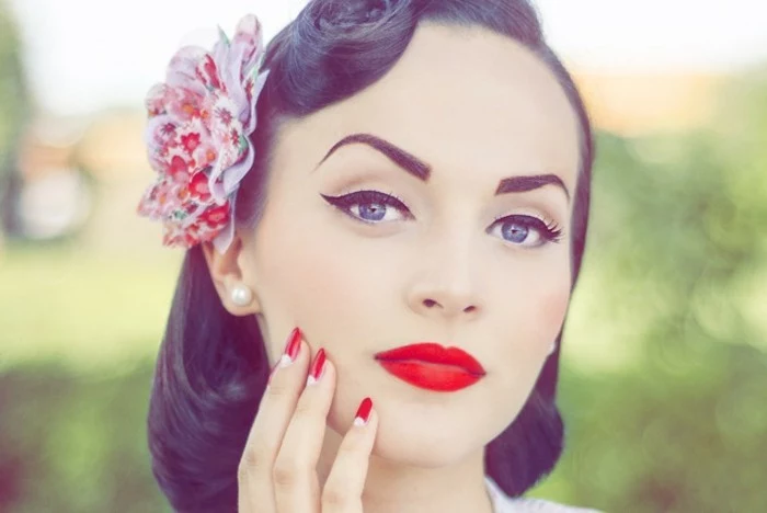 vintage hairstyles, young woman with retro 1950's hairstyle and colorful fake flower hair ornament, pearl earring and heavy make up