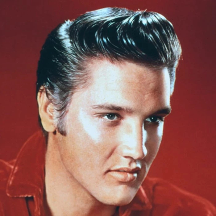 close up of older elvis presley, black gelled up hair, red shirt and background and blue eyes, colorized vintage photo