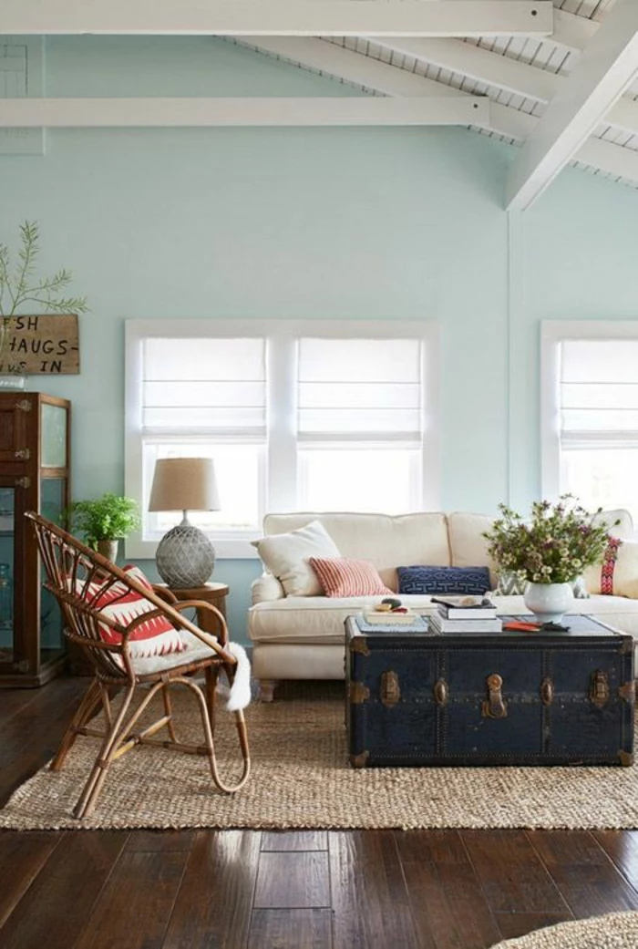 color schemes for living rooms, dark wooden floors, cream chunky carpet, massive old wooden chest used as table, light cream sofa and wooden chair with cushion, light blue walls and white ceiling with wooden beams