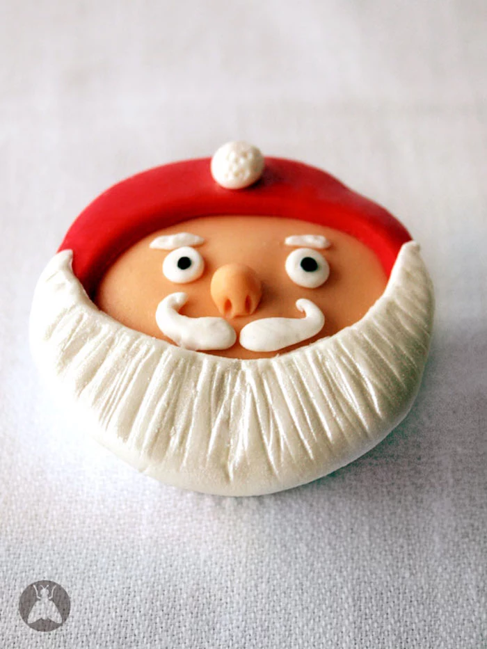 close up of cupcake with orange, red black and white fondant icing, in the shape of santa's head