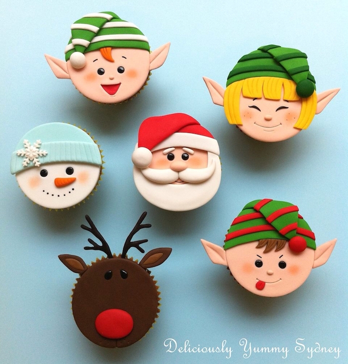 christmas flavors, six cupcakes decorated with colorful fondant icing, made to look like santa, snowman, rudolph and three elves, on pale blue background