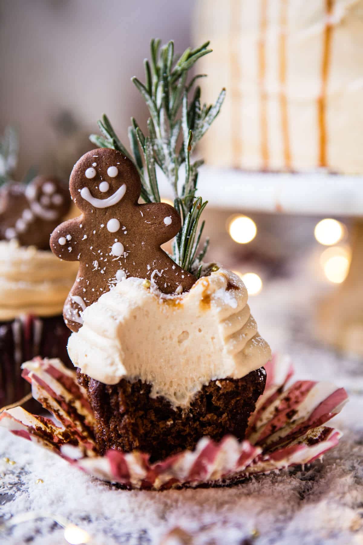 cupcake ideas, unwrapped and bitten dark cupcake, with light brown creamy frosting, decorated with gingerbread man and rosemary stalk