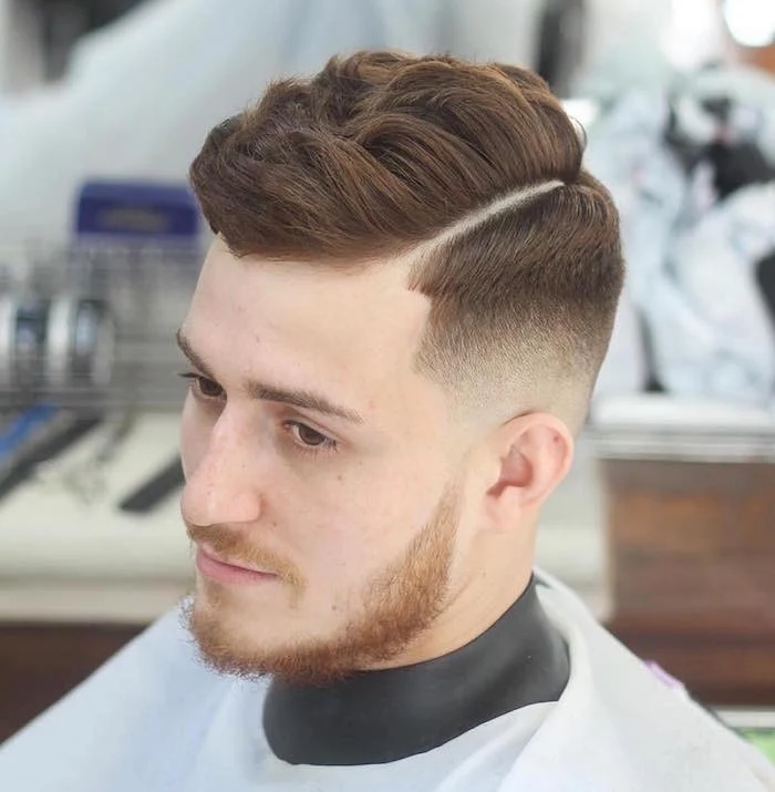 how to style a undercut, young man with auburn hair, cut short on side and longer and wavy on top, seen in close up from above, with red beard and mustache, dark eyes and black and white barber's robe