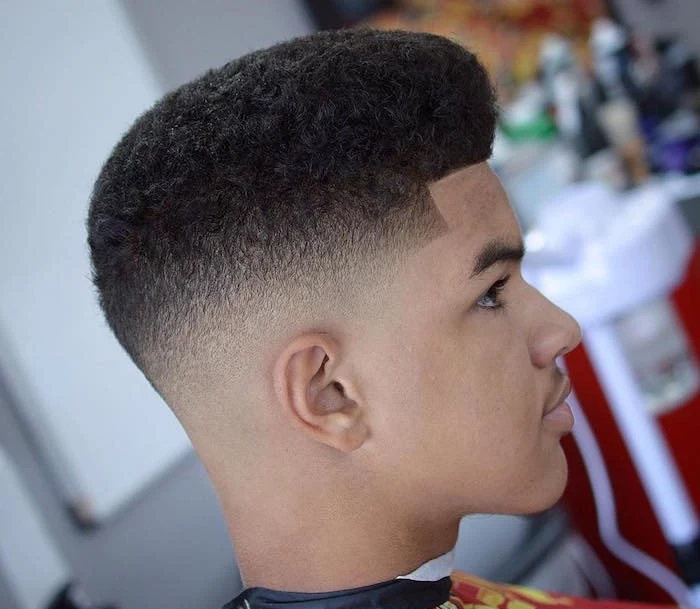disconnected undercut, man with dark afro hair cut short on the sides and long on top, looking sideways in close up