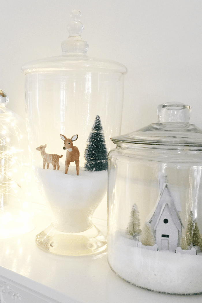 homemade christmas gift ideas, two glass containers filled with fake snow, with two deer and a pine tree, a church and some small tree figurines