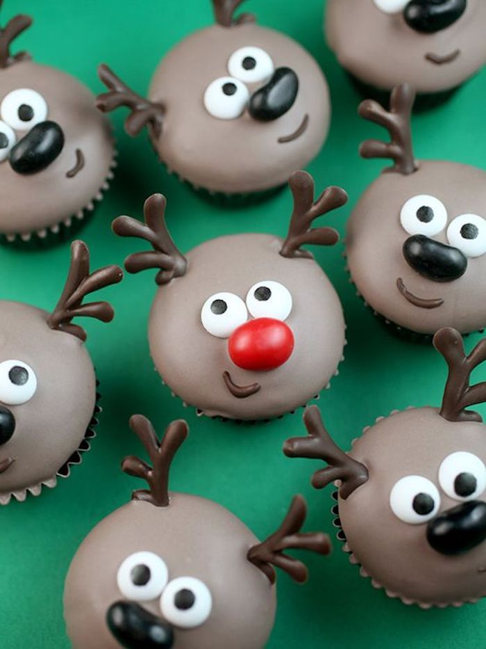 batch of cupcakes with brown frosting, iced with chocolate and made to look like reindeer, middle one has red nose