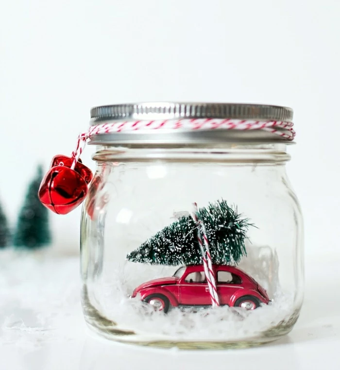 homemade christmas gift ideas, little red car toy with snowy christmas tree figurine tied on its roof, fake snow and white and red string, inside a clear jar with screw cap, two red bells