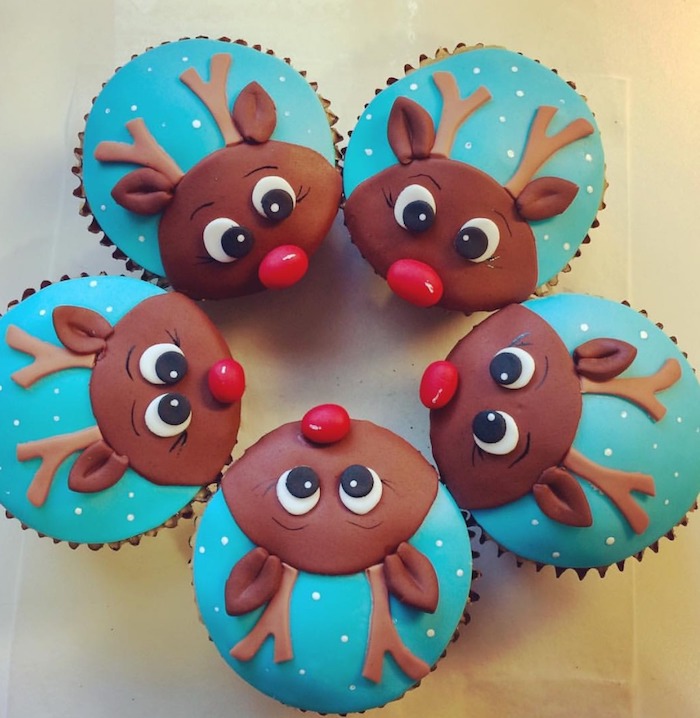 five cupcakes with brown, blue and red fondant icing, made to look like rudolph the reindeer, placed in a circle