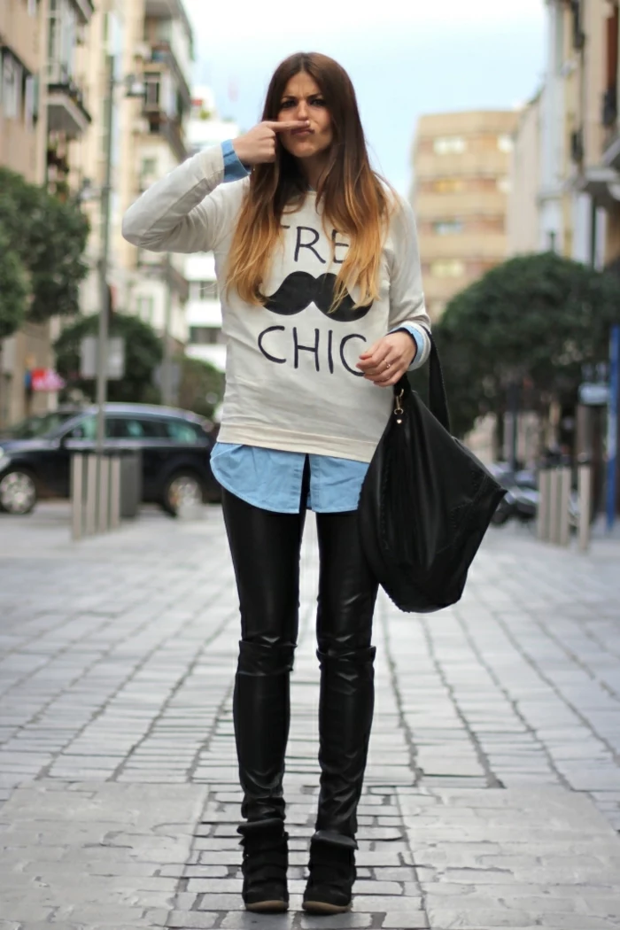 casual business attire, funny photo of young woman, with skinny black leather trousers, denim shirt under white top with black print, black bag and shoes