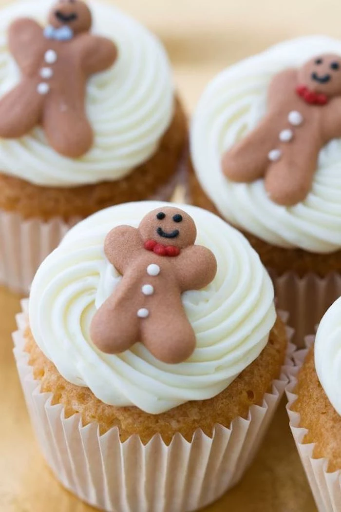 four plain cupcakes, decorated with white frosting, and small gingerbread men