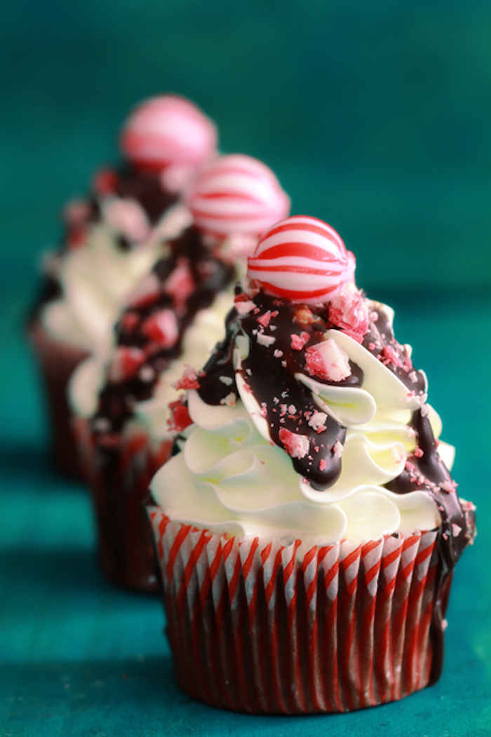 chocolate cupcakes images, three chocolate cupcakes, with whipped cream frosting, decorated with chocolate drizzle, crushed candies and a whole peppermint candy on top