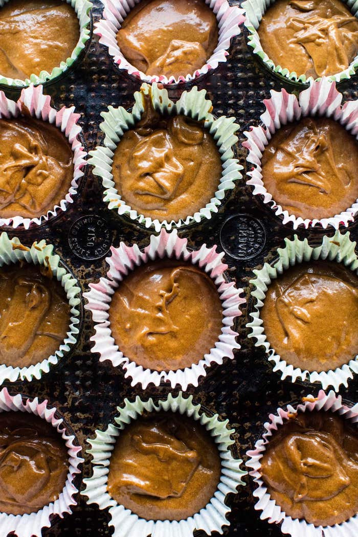 cupcake ideas, twelve red and green cupcake wrappers, inside a black cupcake mould, half-filled with brown batter