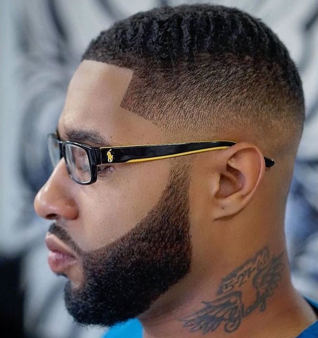 faded undercut, man with polo glasses with black and yellow frames, dark hair cropped very short on the side but kept longer on top, trimmed beard and mustache, tattoo on his neck